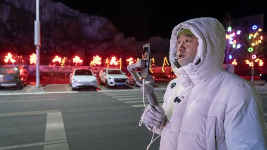 在吉林市阿什哈達霧凇觀景帶，霧凇播報員正在直播。新華社記者 李典 攝