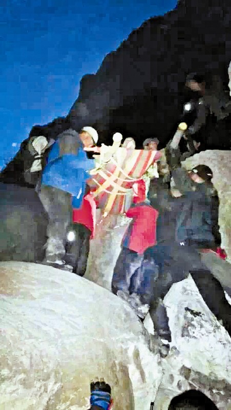 救援隊(duì)員用自制的簡易擔(dān)架抬傷者。