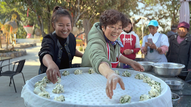 【2】旅居者趙發(fā)英（圖左二）教曼海村村民做花卷。陶思源-攝
